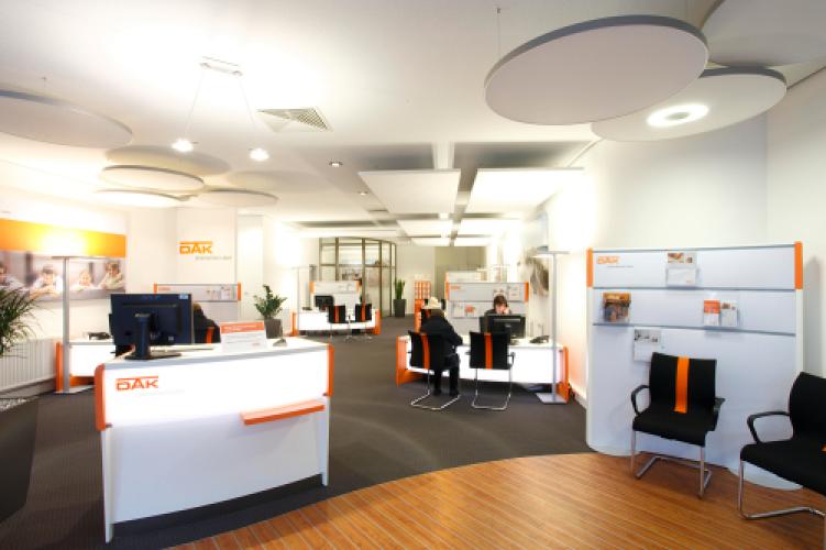 consultation desks in white and orange with backlit front and acoustic ceiling sails in a DAK service centre