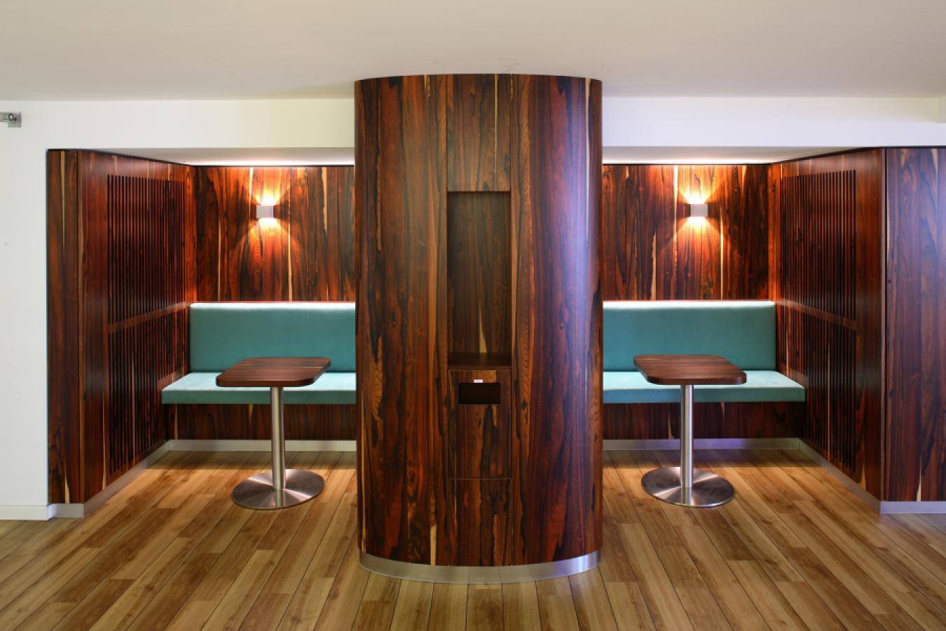 Sitznische mit furniertem Holz und türkisfarbenen Sitzpolstern