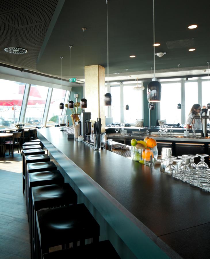 lange Treseninsel mit dunkler Thekenplatte und türkisfarbener Tresenfront und Baldachin im Restaurant Längengrad Kiel