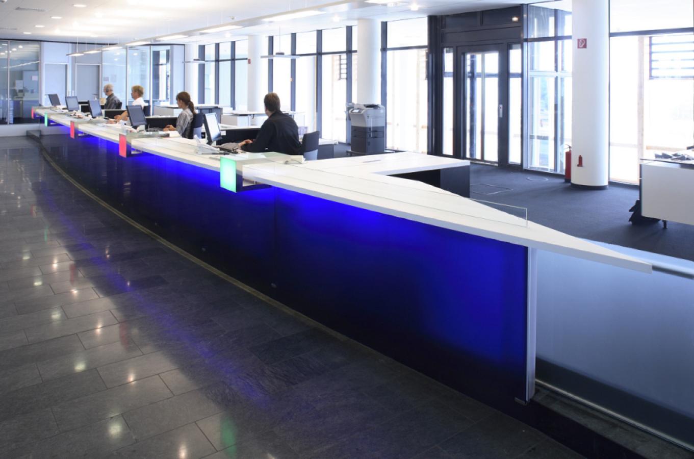 langer Beratungstresen mit Front aus blauem hinterleuchtetem Plexiglas und Tresenplatte aus weißem Mineralwerkstoff am Fährterminal der TT-Line