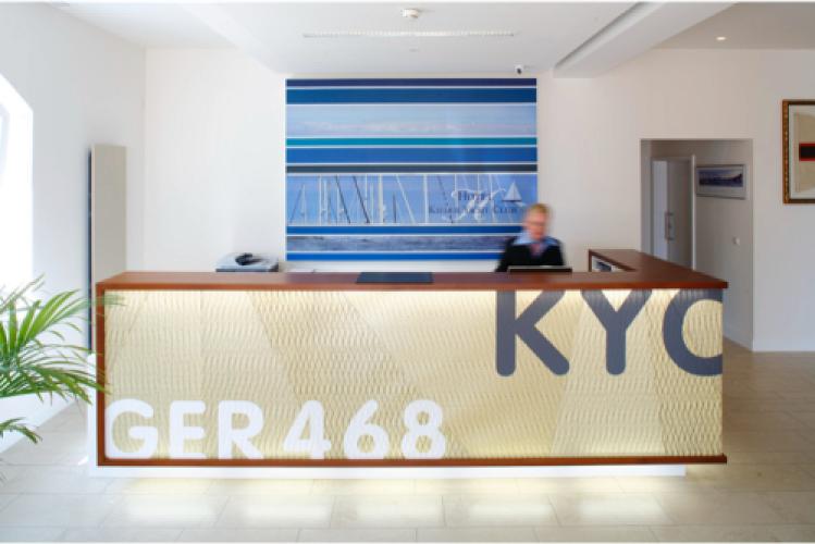 winkeliger Empfangstresen aus Massivholz und einer Frontverkleidung aus bedrucktem Segeltuch im Hotel Kieler Yachtclub